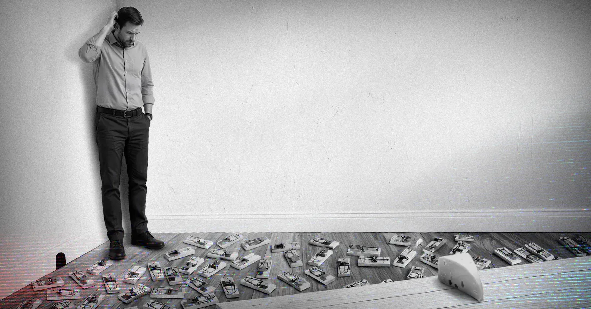 A man stands with his head in his hands looking down at a floor scattered with unused security devices and tools.